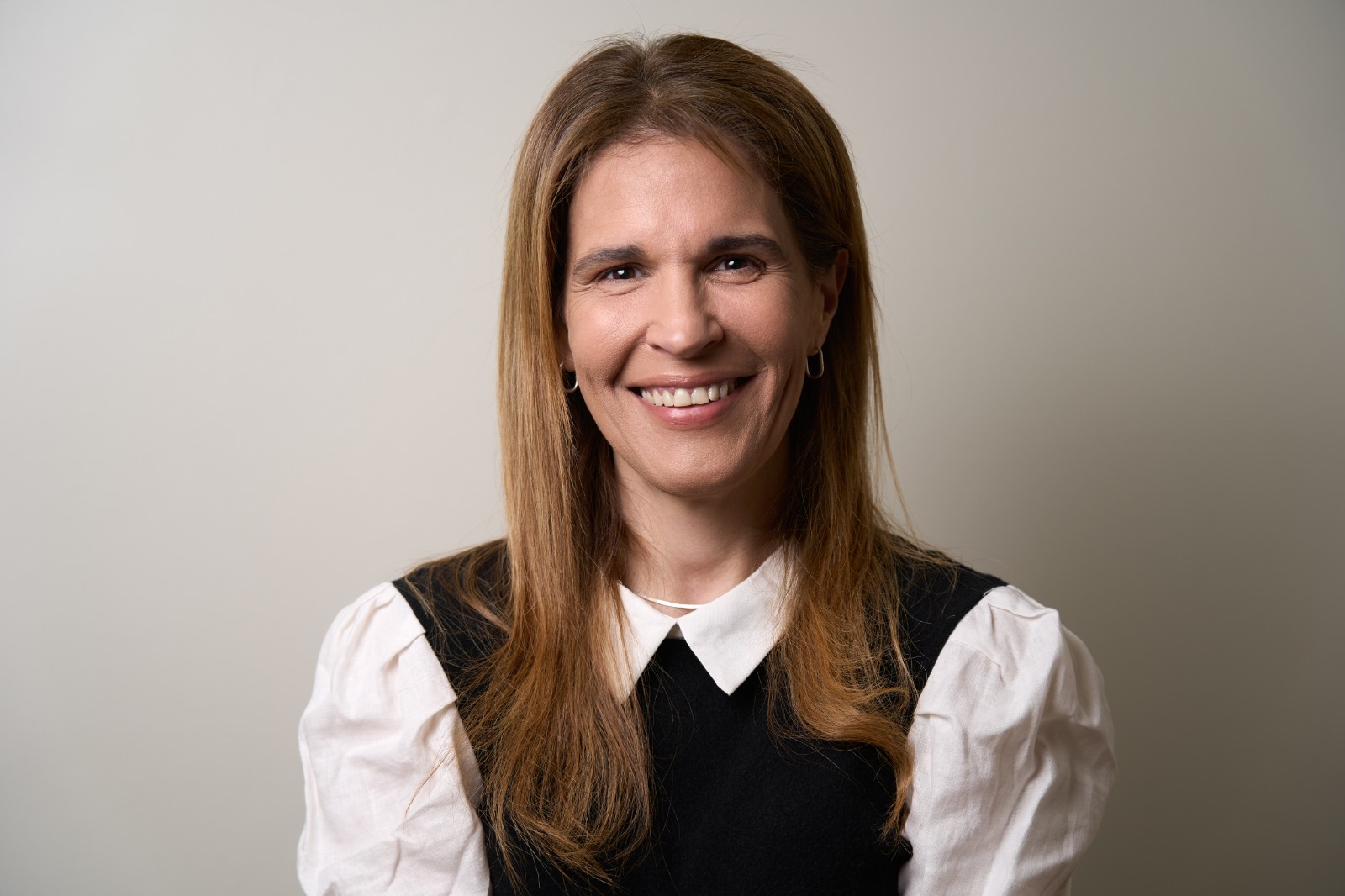 Marianela Rossi, psicóloga clínica, sonriendo con camisa blanca y chaleco negro